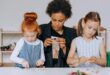 a woman sitting with the girls while holding toys