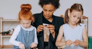 a woman sitting with the girls while holding toys