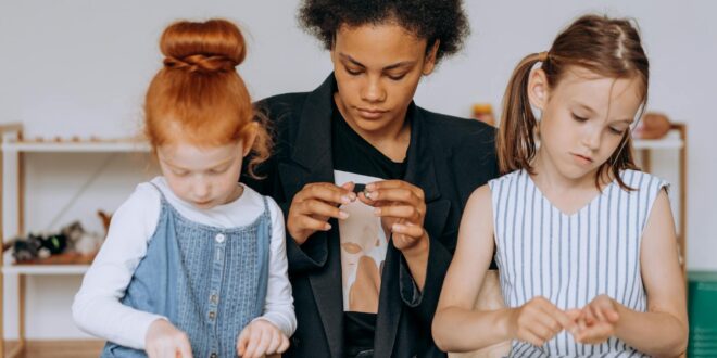 a woman sitting with the girls while holding toys